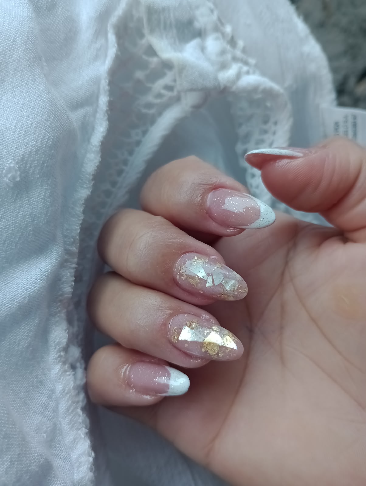 Unhas almond com francesinha branca, glitter e folhas douradas
